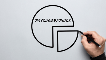 A hand drawing a chart that reads "psychographics" on a whiteboard